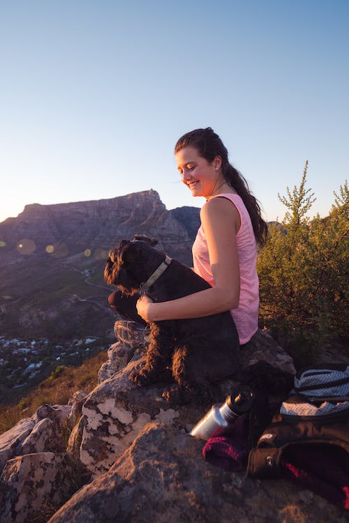 Free Woman Wearing Pink Tank Top Sitting on Rock Beside Dog Stock Photo