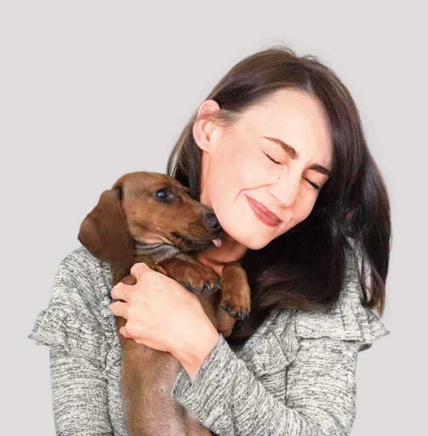 A woman getting licked her face by a dachshound